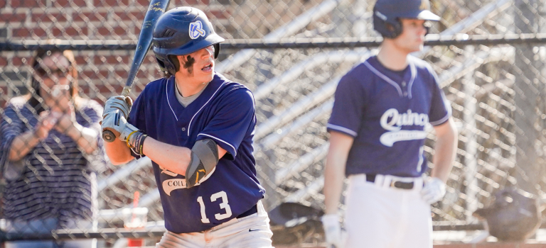 Quincy College baseball player with a bat in hand ready for action